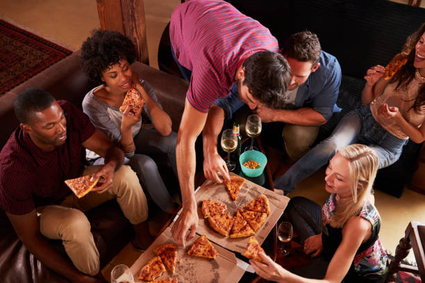 istock Young adults eating pizzas at a party at home, elevated view 684006794