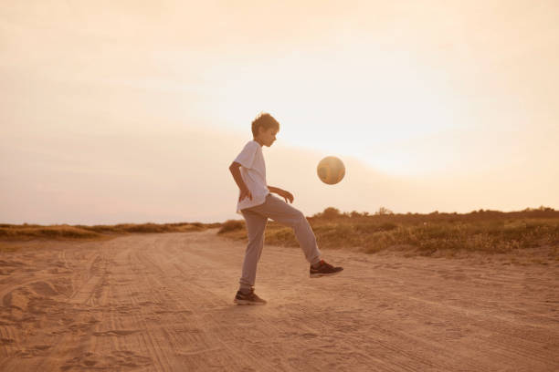 istock Boy playing football at sunset 684041738