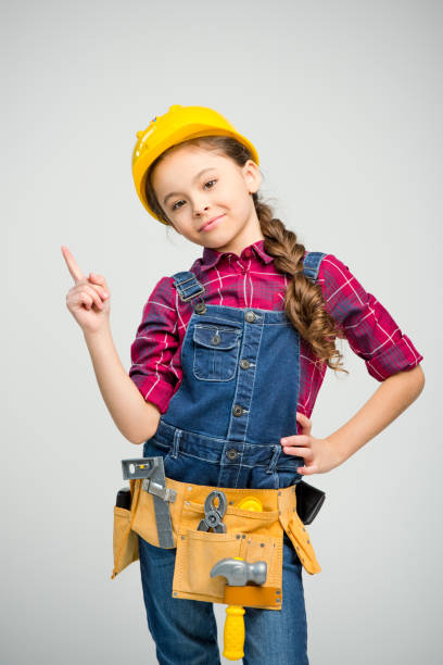 Little girl in tool belt Little girl in tool belt and hard hat pointing up and smiling at camera on white career girl stock pictures, royalty-free photos & images