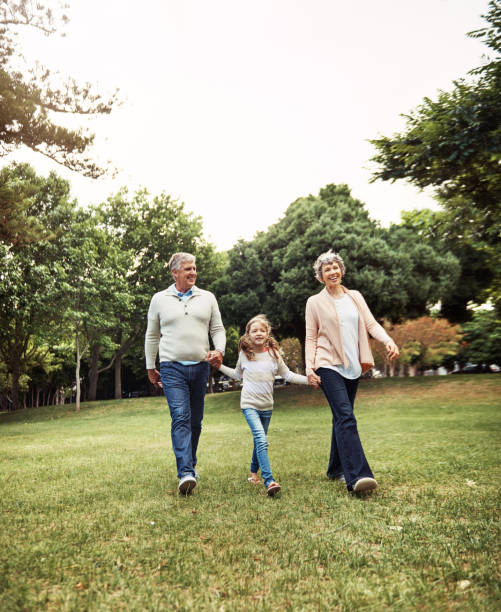Grandparent - a delightful combination of parent, teacher and best friend Shot of a little girl bonding with her grandparents at the park delightful stock pictures, royalty-free photos & images