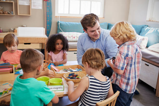 istock Teacher And Pupils Working At Tables In Montessori School 684057364
