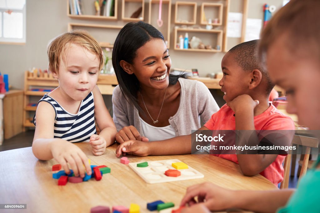 Teacher And Pupils Using Wooden Shapes In Montessori School Teacher Stock Photo