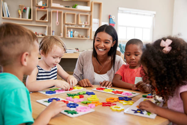 istock Teacher And Pupils Using Flower Shapes In Montessori School 684061684