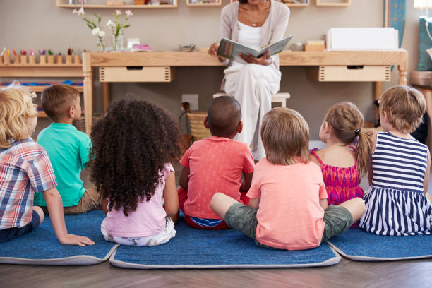 guru di sekolah montessori membaca untuk anak-anak pada waktu cerita - montessori education foto potret stok, foto, & gambar bebas royalti