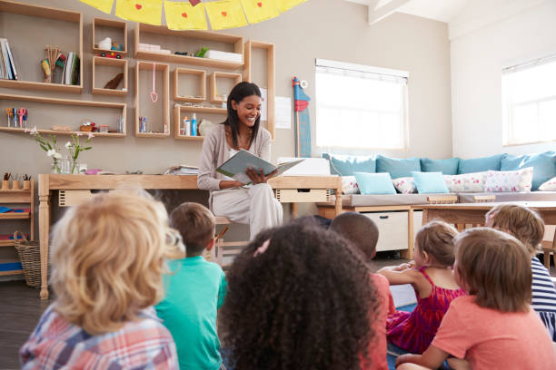 モンテッソーリの学校で教師は、物語の時間に子供たちに読書 - african ethnicity student child group of people ストックフォトと画像