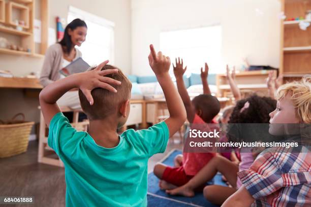 Pupils At Montessori School Raising Hands To Answer Question Stock Photo - Download Image Now