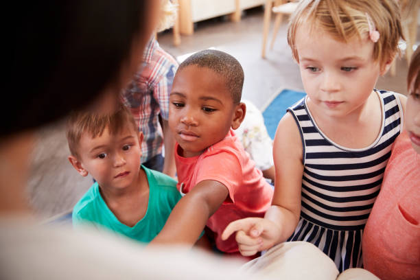 istock Pupils At Montessori School Looking At Book With Teacher 684061974