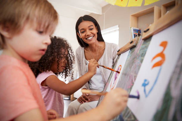 insegnante presso scuola montessori aiutare i bambini in classe d'arte - preschooler preschool child painting foto e immagini stock
