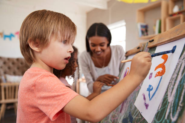 istock Teacher At Montessori School Helping Children in Art Class 684062030