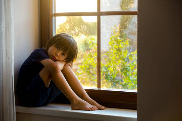 istock Sad child, boy, sitting on a window shield, watching the sunset 684062468