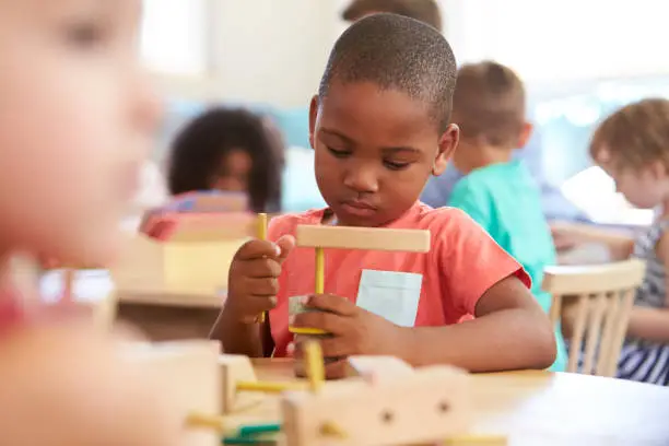 Montessori Pupil Working At Desk With Wooden Shapes