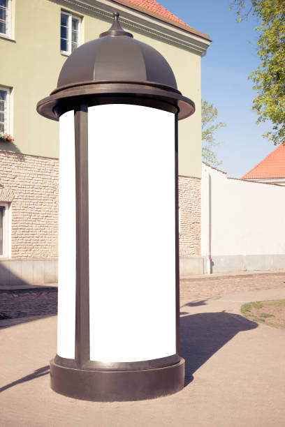 Mock up. Retro style street advertising column stand in the city at sunny day
