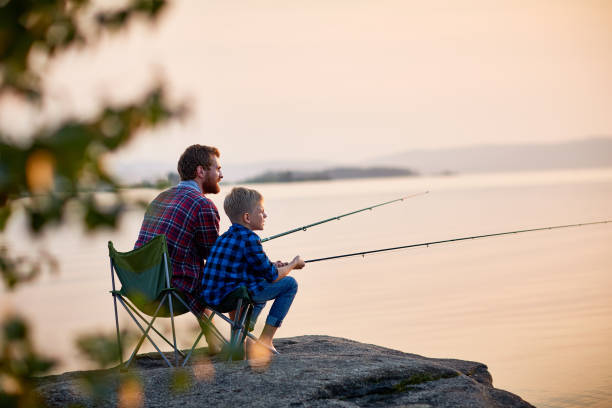 père et fils appréciant la pêche ensemble - fishing photos et images de collection