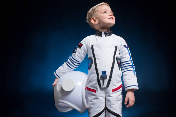 Little boy in space suit Cute little boy in space suit holding helmet and looking at distance cosmonaut stock pictures, royalty-free photos & images