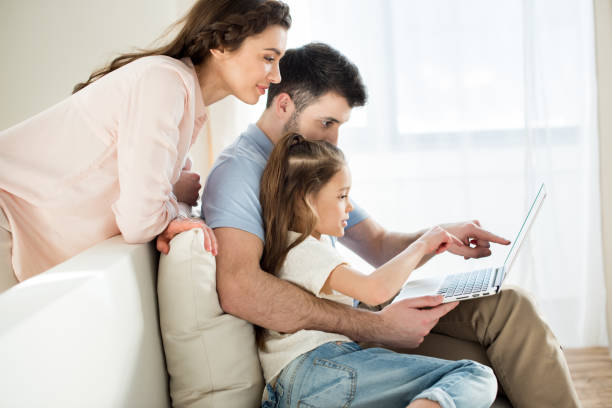istock side view of parents and daughter using laptop at home 684098350