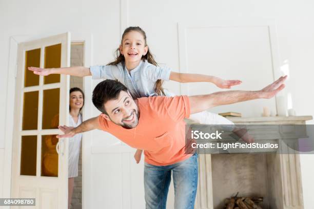 Smiling Mother Watching How Father Playing With Daughter Stock Photo - Download Image Now