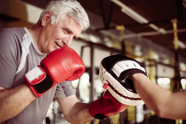 Older man boxing in gym. Senior man with personal trainer. Older man boxing in gym. Senior man with personal trainer. old man boxing stock pictures, royalty-free photos & images