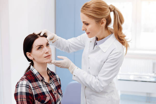 istock Female plastic surgeon looking at her patients face 684105112