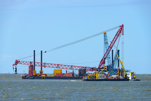 Large construction crane on a barge on a off shore wind turbine construction site in the IJsselmeer off the shore of the Noordoostpolder in the Westermeerwind windfarm.