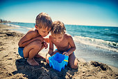 Little boys observing a fish caught in sand bucket