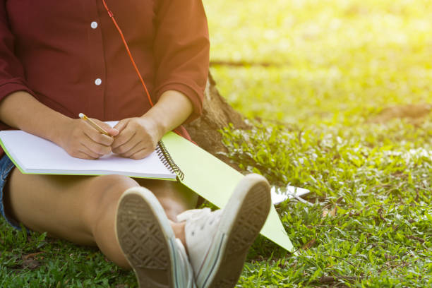 istock Asian women sitting under the tree with blank notebook 684117248