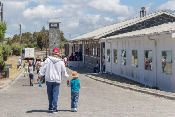 Llittle boy and grandfather visiting the maximum security prison on Robben Island, where Nelson Mandela was imprisoned - Illustrative editorial image ROBBEN ISLAND, SOUTH AFRICA, 18 December 2016: Llittle boy and grandfather visiting the maximum security prison on Robben Island, where Nelson Mandela was imprisoned apartheid sign stock pictures, royalty-free photos & images