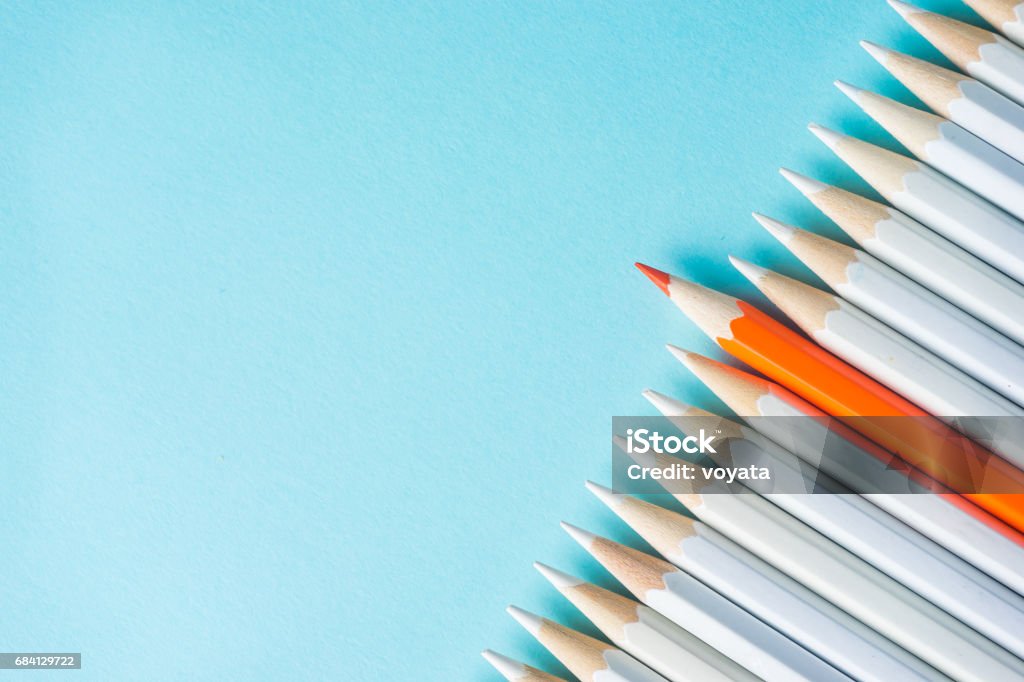 lot of white pencils and color pencil on blue paper background. Business concept - lot of white pencils and color pencil on blue paper background. It's symbol of fight, leadership and communication. Pencil Stock Photo