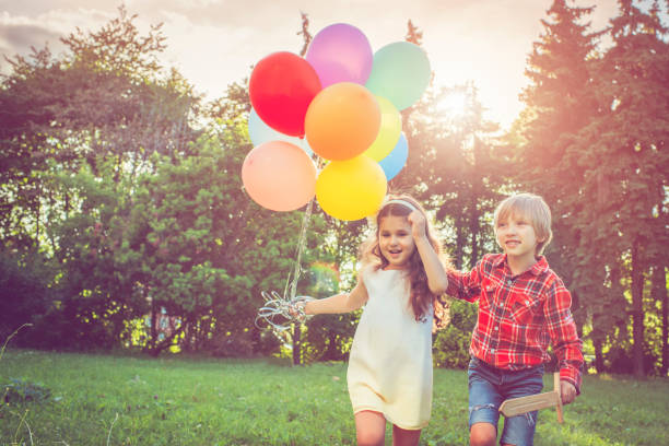 маленький мальчик и девочка с воздушными шарами - child balloon outdoors little boys стоковые фото и изображения