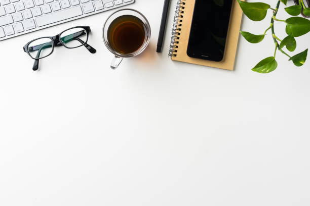 istock Top view of white desktop background with notebook, coffee, smart phone... 684130304