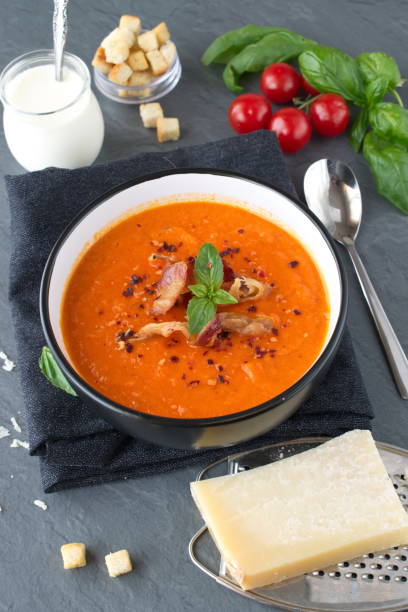 istock Thick tomato soup with basil and fried bacon in a black ceramic bowl on a grey abstract background. Healthy eating concept 684140856