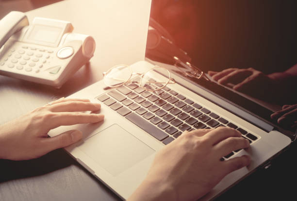 istock Hand on Laptop computer on sunny office desk with phone 684144604