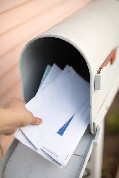 Letters in a mailbox are being held by a hand. stock photo