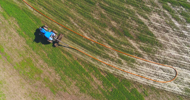 istock Tractor fertilizing field with liquid manure pumped from remote tanker. 684155560
