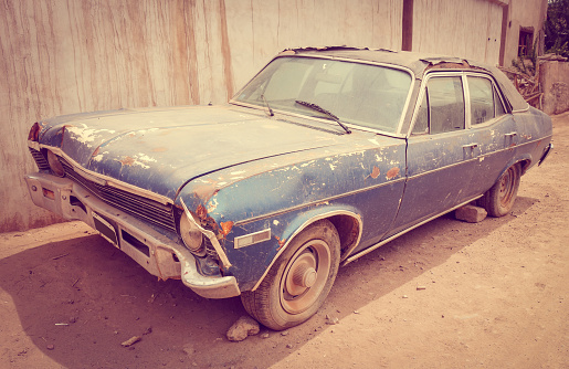 Coche viejo, deteriorado, sobre fondo blanco.