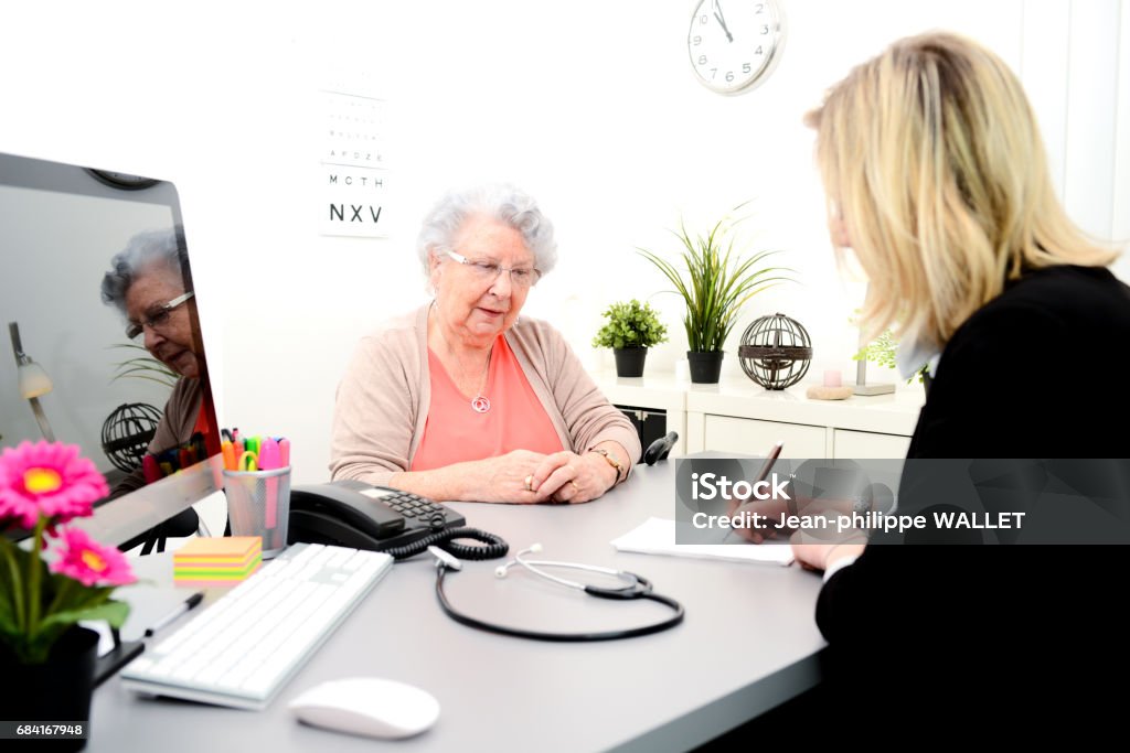 Femme d’âge mûr médecin dans son bureau écrivant une prescription de médicament à une vieille femme âgée - Photo de Adulte libre de droits