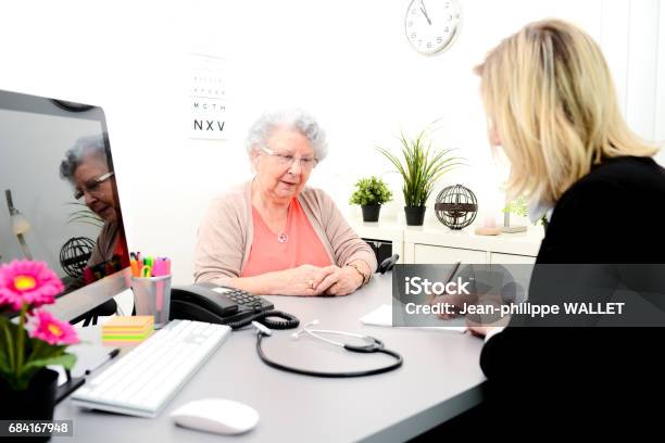 Photo libre de droit de Femme Dâge Mûr Médecin Dans Son Bureau Écrivant Une Prescription De Médicament À Une Vieille Femme Âgée banque d'images et plus d'images libres de droit de Adulte