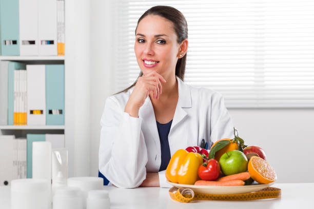 dietologo femminile che mostra verdure e frutta - orange uniform foto e immagini stock