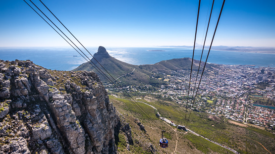 View of the cable car going up Table Mountain with a dramatic landscape of Cape Town. Taken from the top of Table Mountain, looking down on the city. Lions Head can also be seen in the background. Taken in April 2017 - Fall/Autumn.