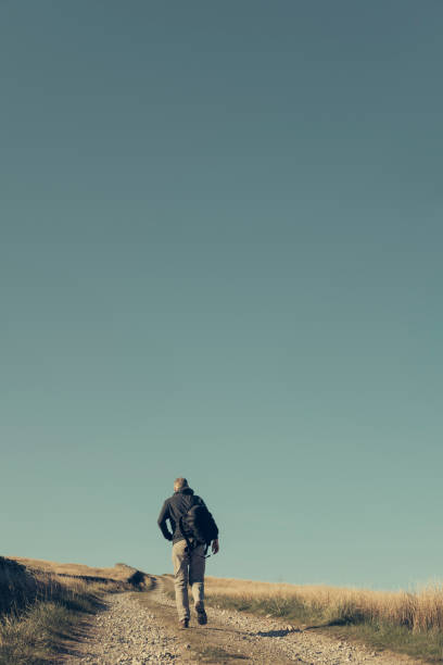 istock Man hiking up a remote country dirt road. 684470990