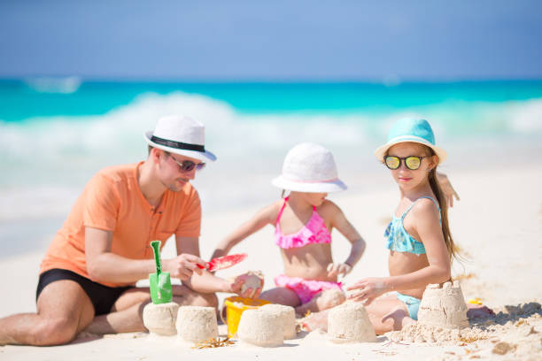 istock Father and little daughters making sand castle at tropical beach 684505262