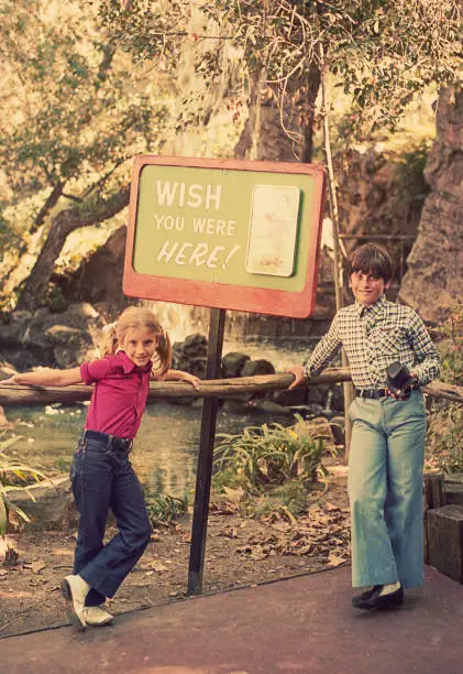 Vintage image featuring a couple of kids standing beside a location sign