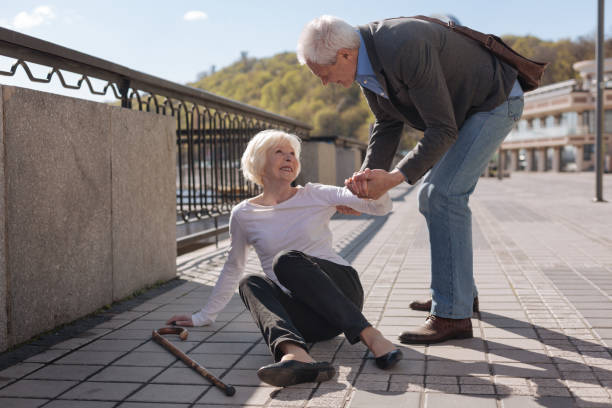 Happy retired family solving their problems in the street Always rescue each other. Old pretty cheerful woman lying on the ground and smiling while polite husband helping her t cell photos stock pictures, royalty-free photos & images