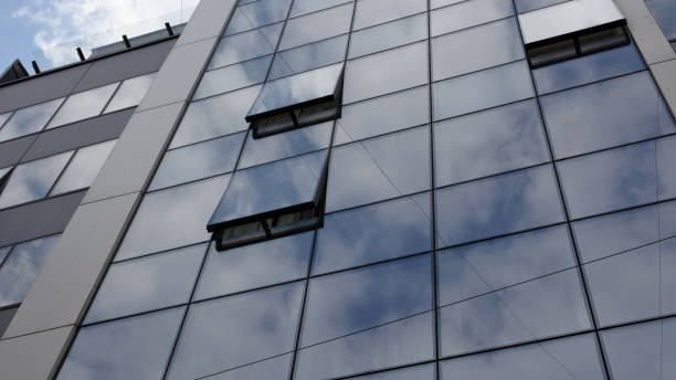 istock Modern business building windows. Blue Glass Facade with Geometric Lines and Clouds Reflecting. 684542530