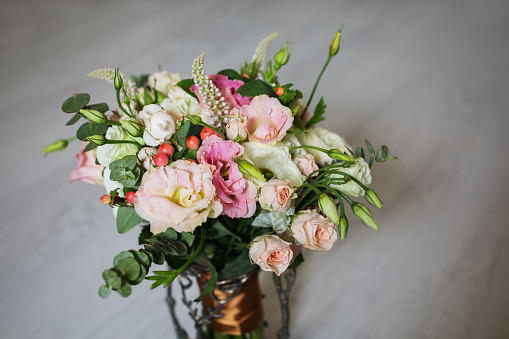Wedding bouquet of white, red and pink flowers in a vintage vase stands on a light background. White and pink roses. Morning bride, copyspace