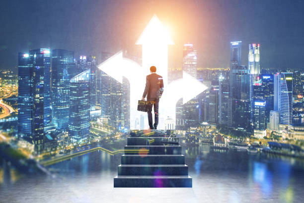 Rear view of a businessman with a suitcase standing on the stairs near a three arrow opening in a wall choosing his way. Cityscape in the background. Toned image