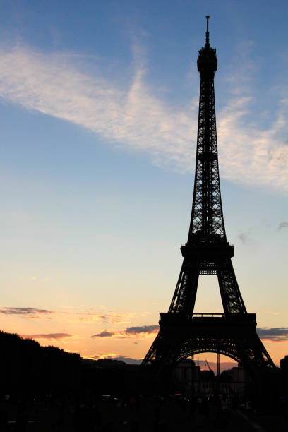 силуэт эйфелевой башни во время красочного заката, париж, франция - champ de mars flash стоковые фото и изображения