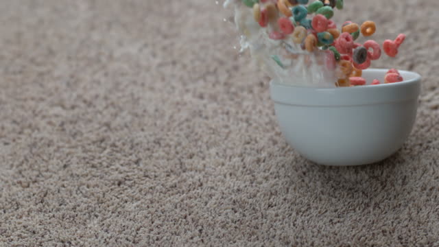 Bowl of cereal spilling on carpet in slow motion