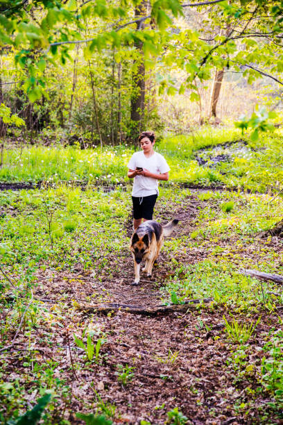 istock Preteen boy walking with his dog in a forest using a phone with ear buds. 684612148