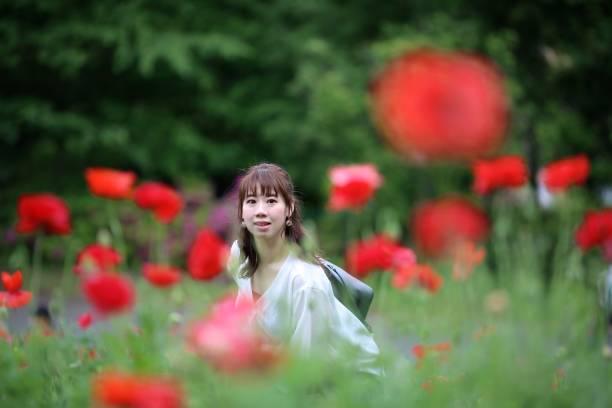 joven disfrutando de flores en el parque - poppy oriental poppy plant spring fotografías e imágenes de stock