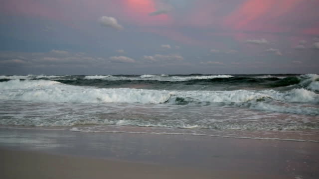 Waves on beach colored sky.